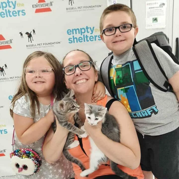 Mother and two children holding two kittens adopted at Empty the Shelters