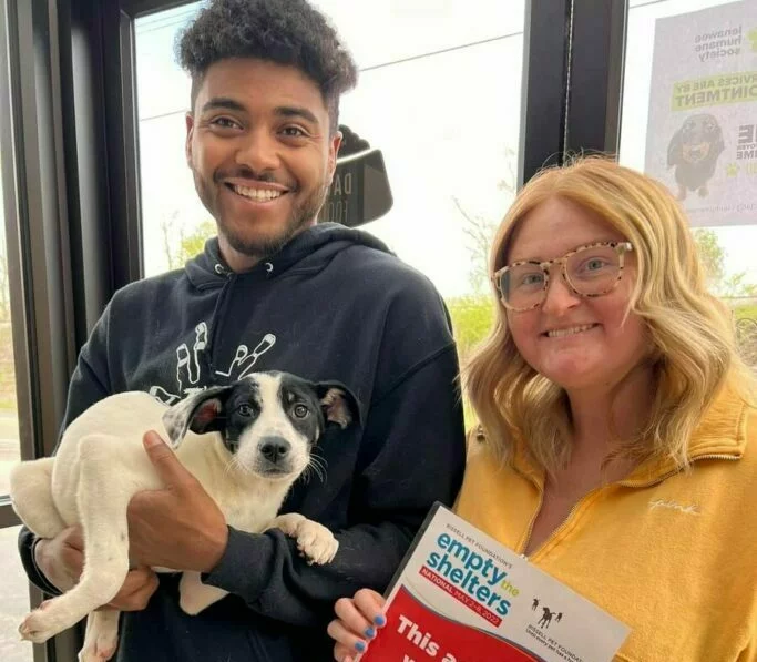 A couple with their adopted black and white puppy at an Empty the Shelters event