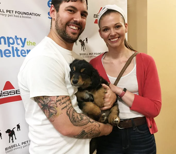 A couple adopting a puppy at an Empty the Shelters event