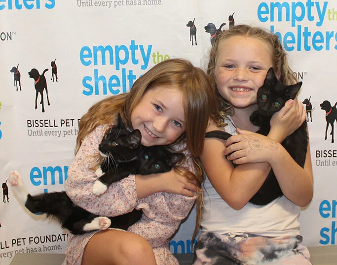 Girls holding 3 black kittens at Empty the Shelters